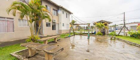 A building with a covered outdoor area, a concrete courtyard, and a palm tree.