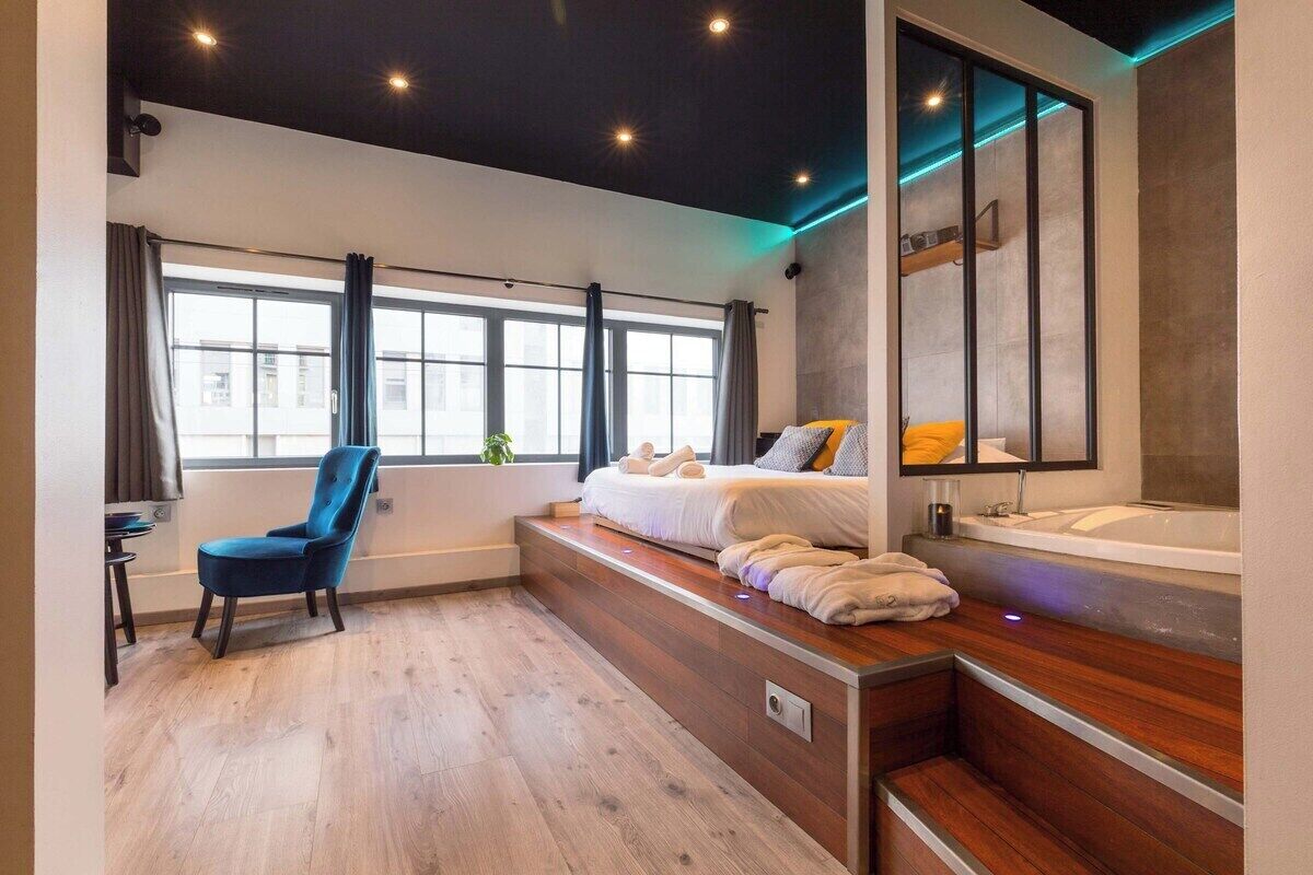 Een moderne hotelkamer met een bed, een zithoek, een groot raam en een bad.