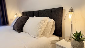 A neatly made bed with white and gray bedding, a modern lamp, and a small plant on a bedside table. - 4 Bed | Free Parking | Fast WiFi | Desk | Pets (Buckshaw Village)