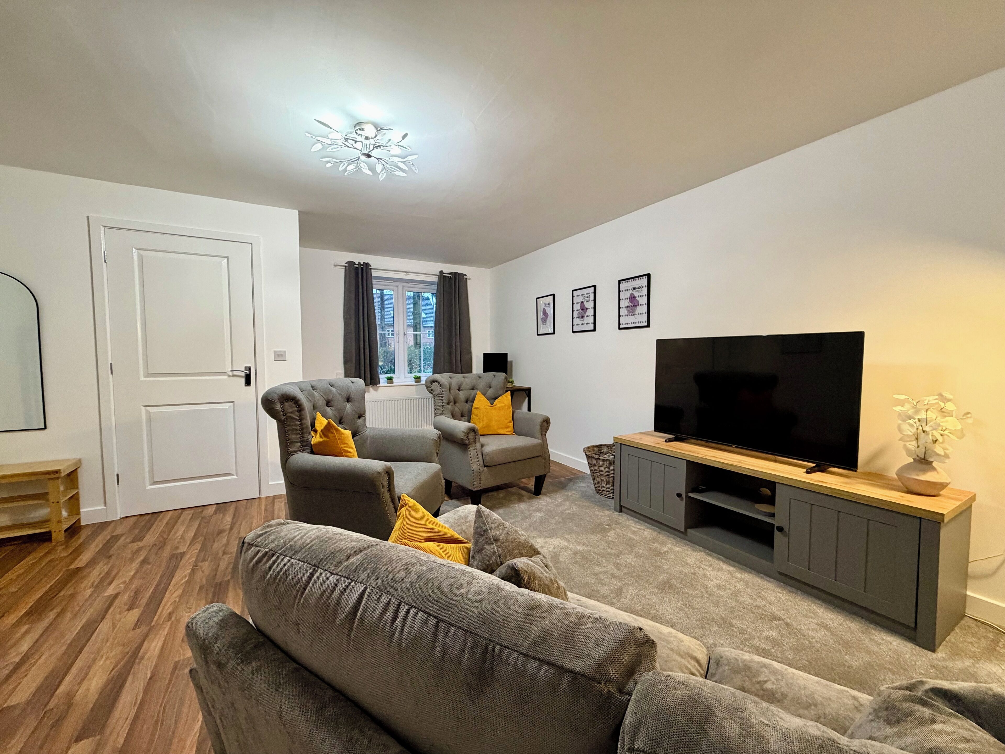 A living room with a sofa, armchairs, a TV, and a wooden cabinet.