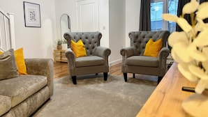 A living room with two grey armchairs, each with a yellow pillow, a grey sofa, and a wooden coffee table. - 4 Bed | Free Parking | Fast WiFi | Desk | Pets (Buckshaw Village)