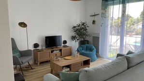 En moderne stue med sofa, fjernsyn, sofabord og en potteplante.