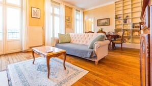Una sala de estar con un sofá, una mesa de centro, una estantería y una ventana con cortinas.