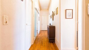 Un pasillo con paredes blancas, suelo de madera y un mueble de madera oscura.