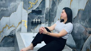 A person seated on a bathtub in a bathroom with marble walls and a modern design. - Vibe & Stay - Staycation home near Tagaytay (Nasugbu)