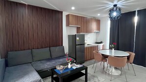 A modern living room with a sofa, coffee table, and dining area with chairs. - Vibe & Stay - Staycation home near Tagaytay (Nasugbu)