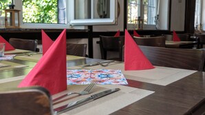A restaurant table set with red napkins, a floral placemat, and cutlery. - Landgasthof Hieren Mühle (Boppard)
