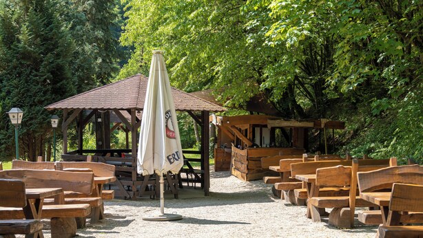A rustic outdoor seating area with wooden benches and tables, a covered pavilion, and a gravel path. - Landgasthof Hieren Mühle (Boppard)