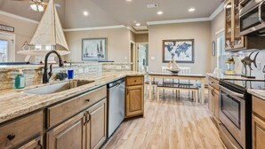 Una cocina moderna con armarios de madera, una isla grande y una zona de comedor con mesa y sillas.