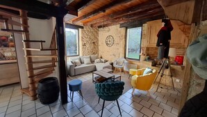Uma sala de estar aconchegante com uma parede de pedra, uma escada de madeira e uma janela grande.