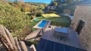 Um deck de madeira com piscina, mesa e cadeiras.
