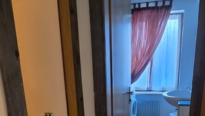 Pasillo que conduce a un baño con ventana, radiador y cortina de ducha.