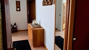 Un pasillo con un banco de madera, un espejo y una puerta.