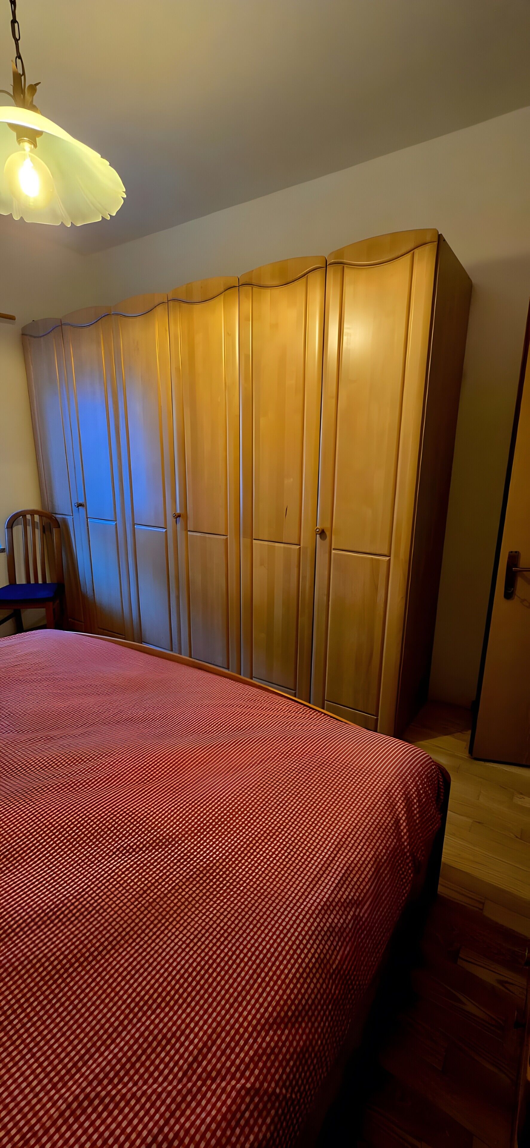 A bedroom with a bed, a wardrobe, and a chair.