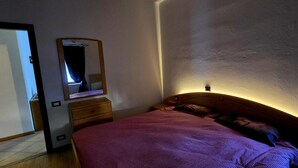 Un dormitorio con cama, cómoda, espejo y ventana.