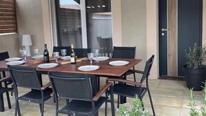 A dining area with a wooden table set for six, black chairs, and a bottle of wine. - Superb air-conditioned villa with pool near Avignon (Tavel)