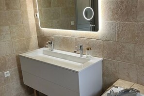 A bathroom with a white vanity, a mirror with a light, and a handheld showerhead. - Superb air-conditioned villa with pool near Avignon (Tavel)