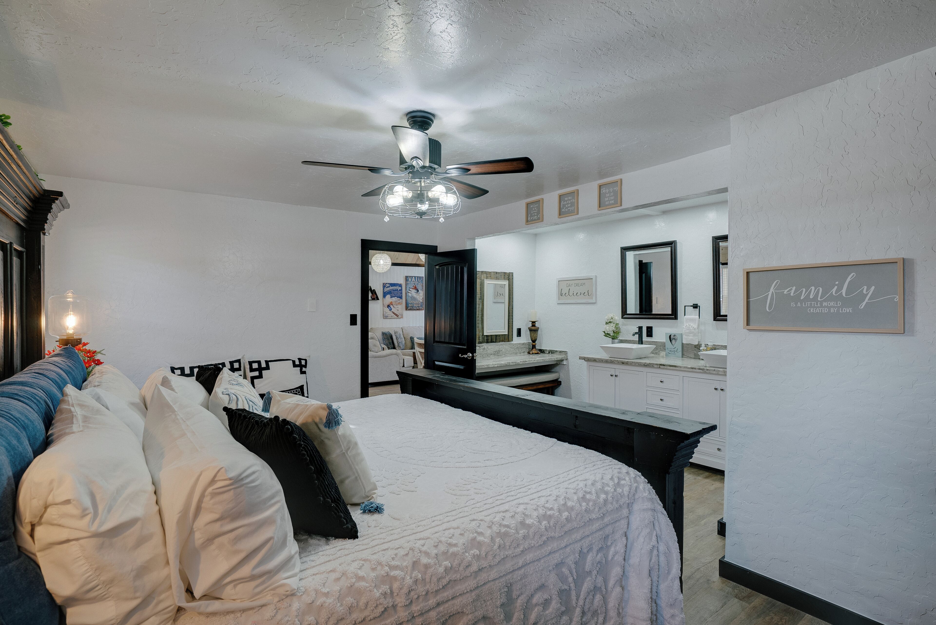 A bedroom with a bed, a ceiling fan, a dresser, and a mirror.