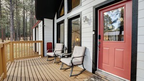 A wooden deck with rocking chairs and a red door. - Getaway in the trees (Angel Fire)