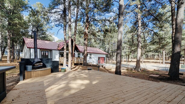 A cabin with a wooden deck, a chimney, and a small porch. - Guest house escape in the trees (Angel Fire)