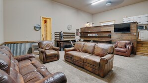 A living room with leather sofas, a wooden entertainment unit, and a television. - Guest house escape in the trees (Angel Fire)