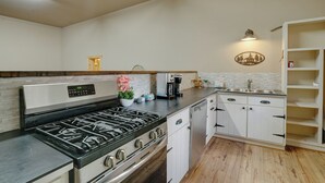 A kitchen with a gas stove, dishwasher, white cabinets, and a wooden countertop. - Guest house escape in the trees (Angel Fire)