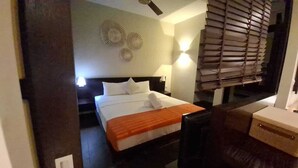 A hotel room with a bed, bedside tables, a desk, and a window with blinds. - Luxury Furnished Apartment in Grand Baie (Grand Baie)