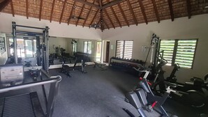 A gym with exercise equipment, mirrors, and windows. - Luxury Furnished Apartment in Grand Baie (Grand Baie)