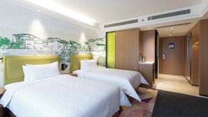 Une chambre d’hôtel avec deux lits, un petit bureau et une fresque murale.
