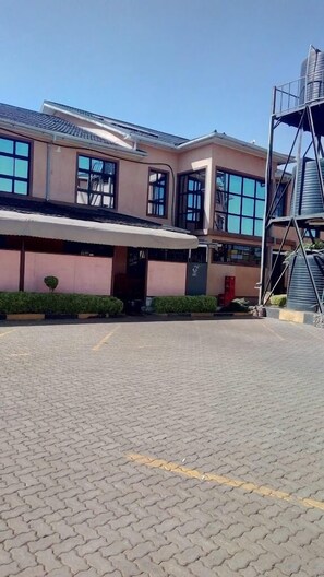 A building with a covered entrance, a staircase, and a paved area.