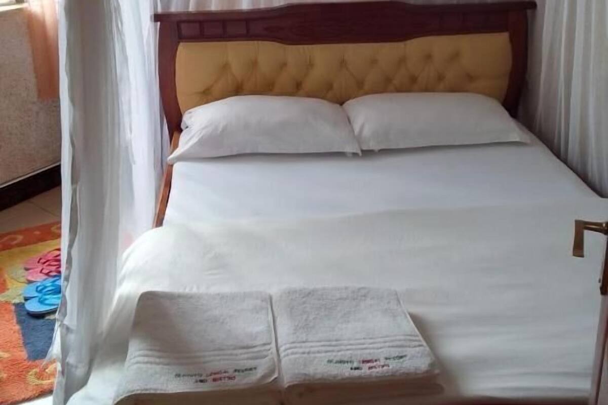 Un lit à baldaquin, avec une tête de lit en bois et deux oreillers.