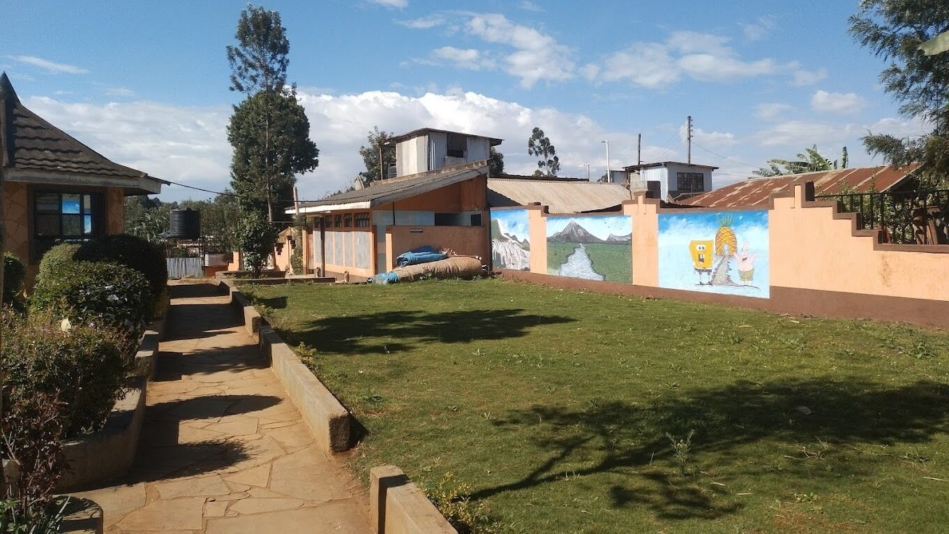 Zona residencial con sendero pavimentado, césped y un mural en la pared de un edificio.