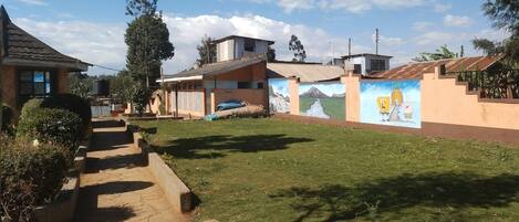 A residential area with a paved pathway, a grassy lawn, and a mural on a building wall.