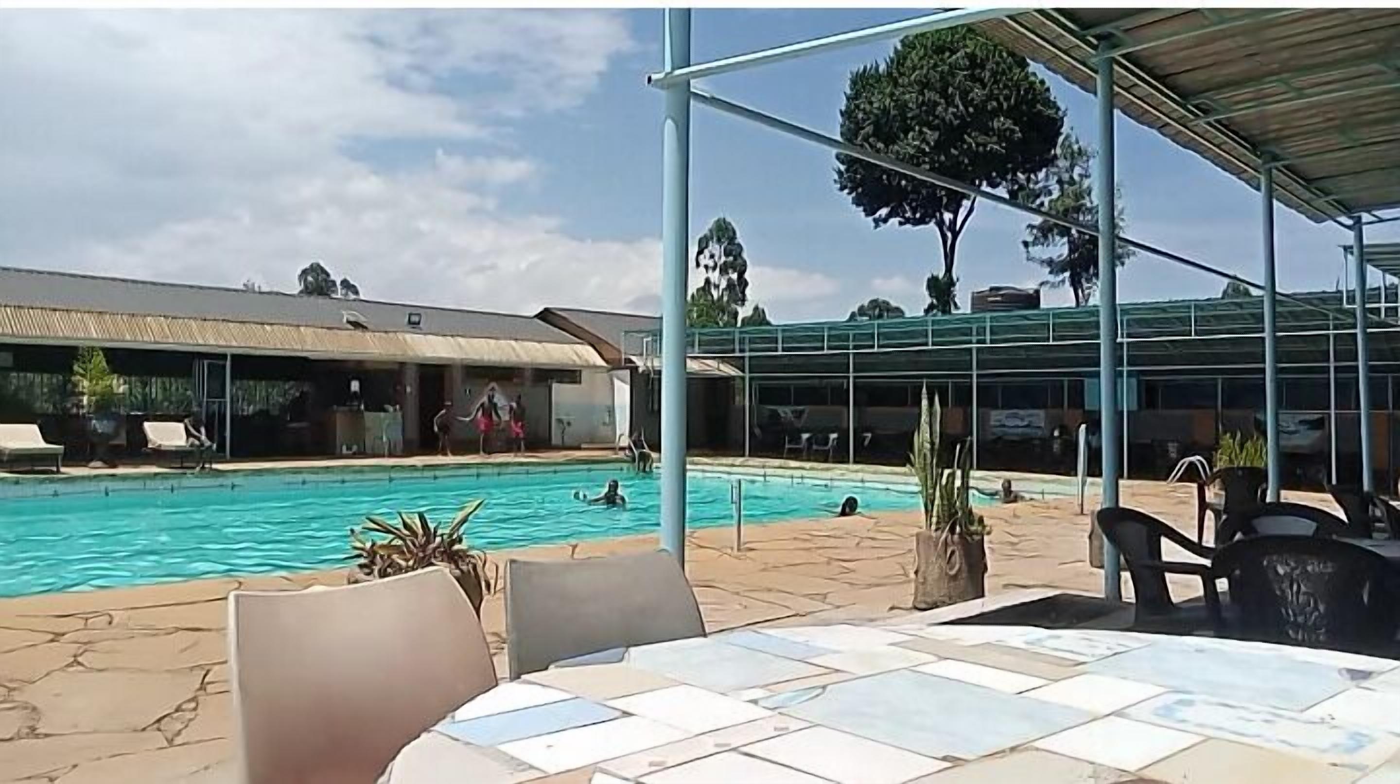 Ein Swimmingpool mit Liegestühlen und einer überdachten Sitzgelegenheit.