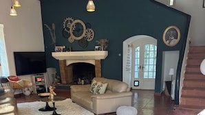 Uma sala de estar ampla com lareira, um sofá, uma televisão e uma escada.