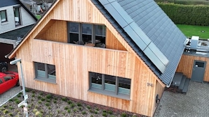Una moderna casa in legno con tetto spiovente e ampie finestre.