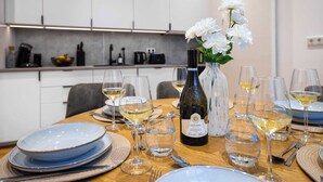 Une table à manger dressée avec des assiettes, des verres et une bouteille de vin, et un vase de fleurs placé au centre.