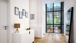 Un intérieur moderne avec un meuble blanc, des certificats encadrés, une lampe et une grande porte vitrée donnant sur un espace extérieur.
