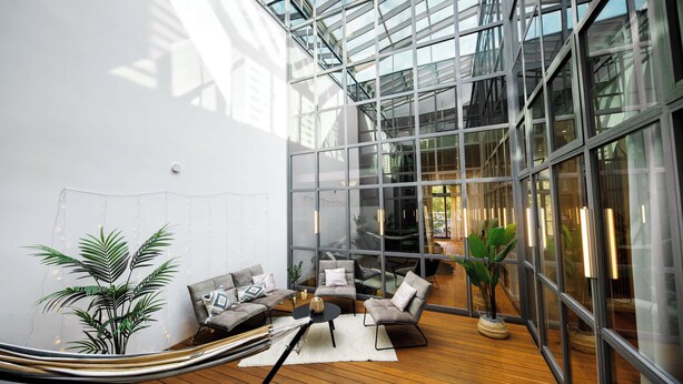 Un intérieur moderne avec un plafond en verre, un plancher en bois et des meubles contemporains.