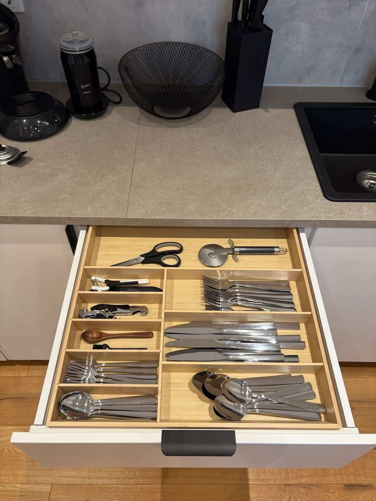 Una cocina con un cajón que contiene diversos utensilios.