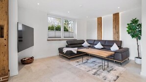 Una sala de estar moderna con un sofá modular, una mesa de centro y un ventanal grande.