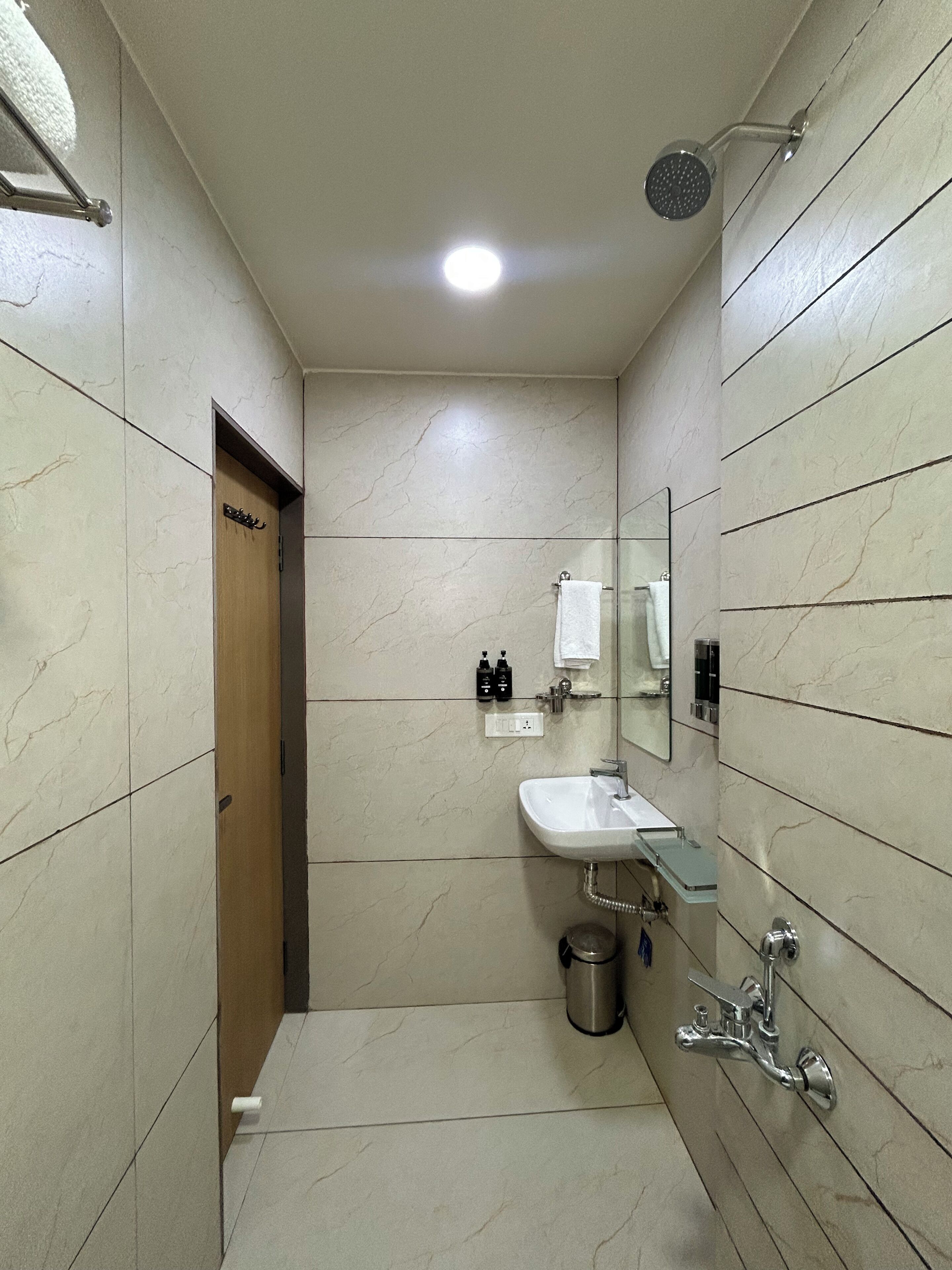 Une salle de bain équipée d’un lavabo, d’un miroir, d’une douche et d’un porte-serviettes.