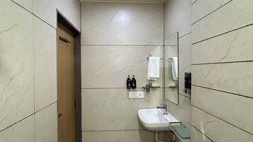 Une salle de bain équipée d’un lavabo, d’un miroir, d’une douche et d’un porte-serviettes.