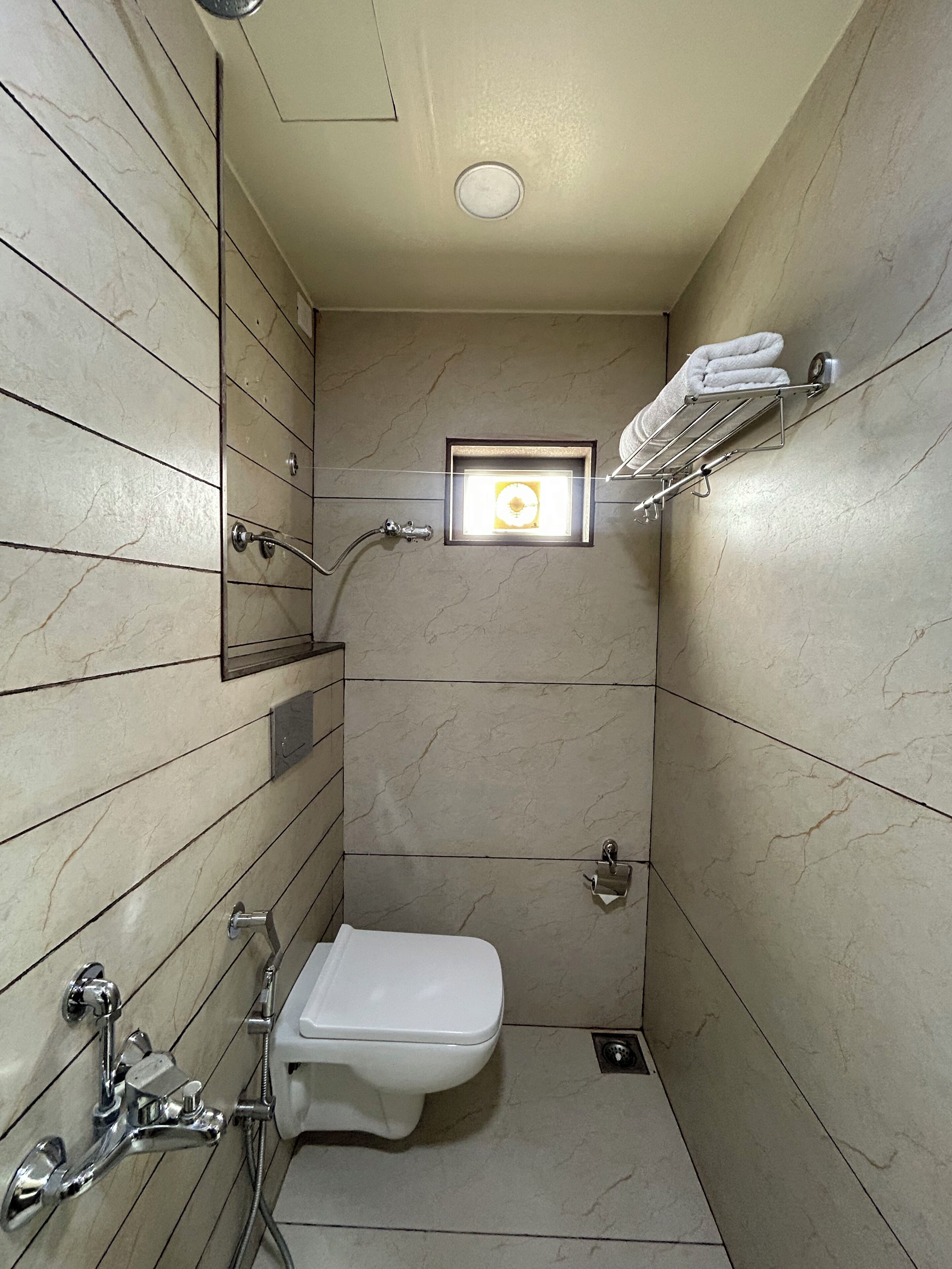 Un baño pequeño con inodoro, ducha y perchero.