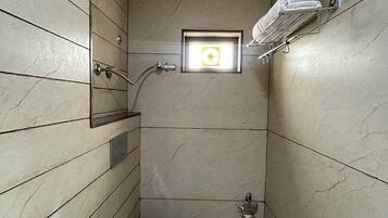 Un baño pequeño con inodoro, ducha y perchero.