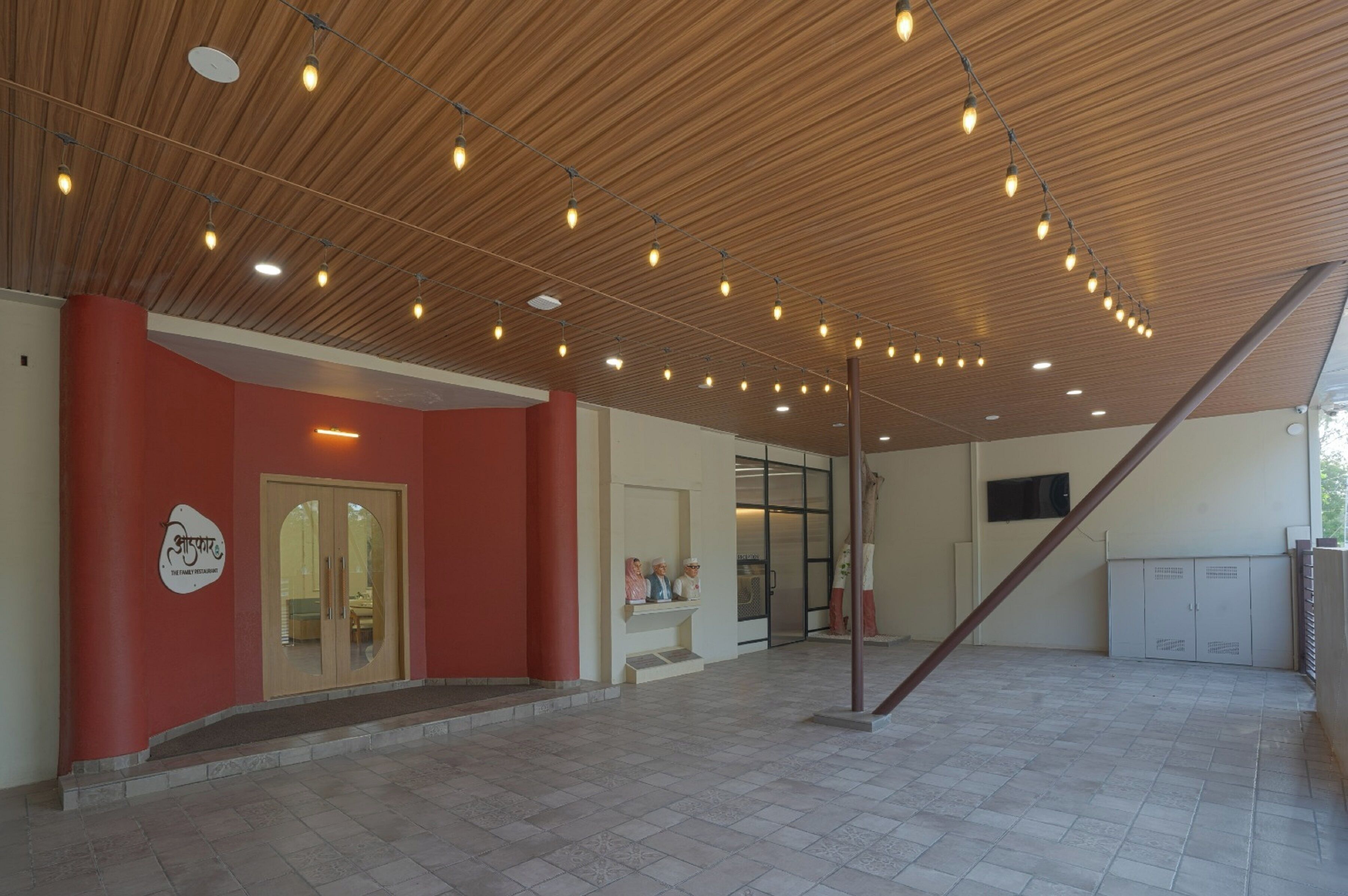 A spacious indoor area with a wooden ceiling, a red wall, and a door with glass panels.