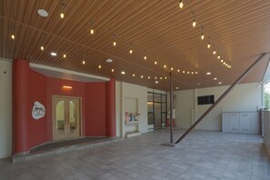 A spacious indoor area with a wooden ceiling, a red wall, and a door with glass panels.