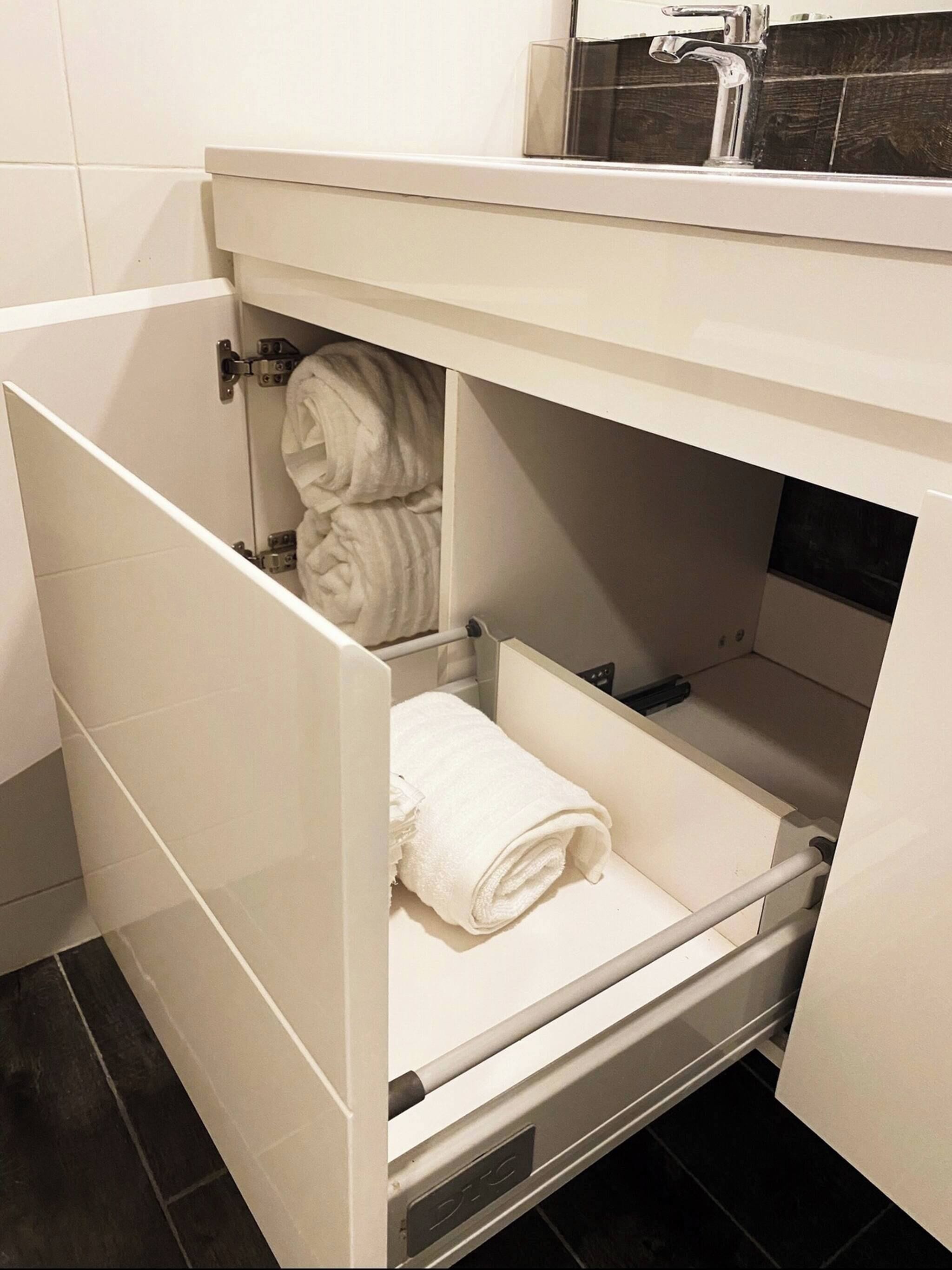 A bathroom with a white vanity, a towel rack, and a shower area.