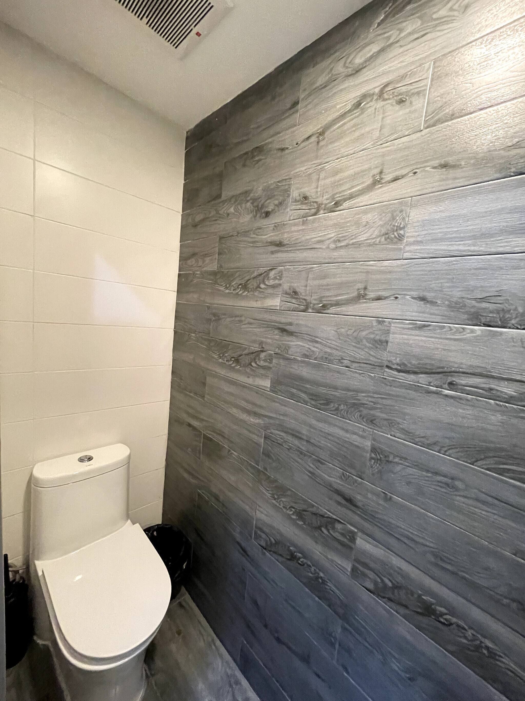 Un baño con inodoro y una pared con diseño que imita la madera.