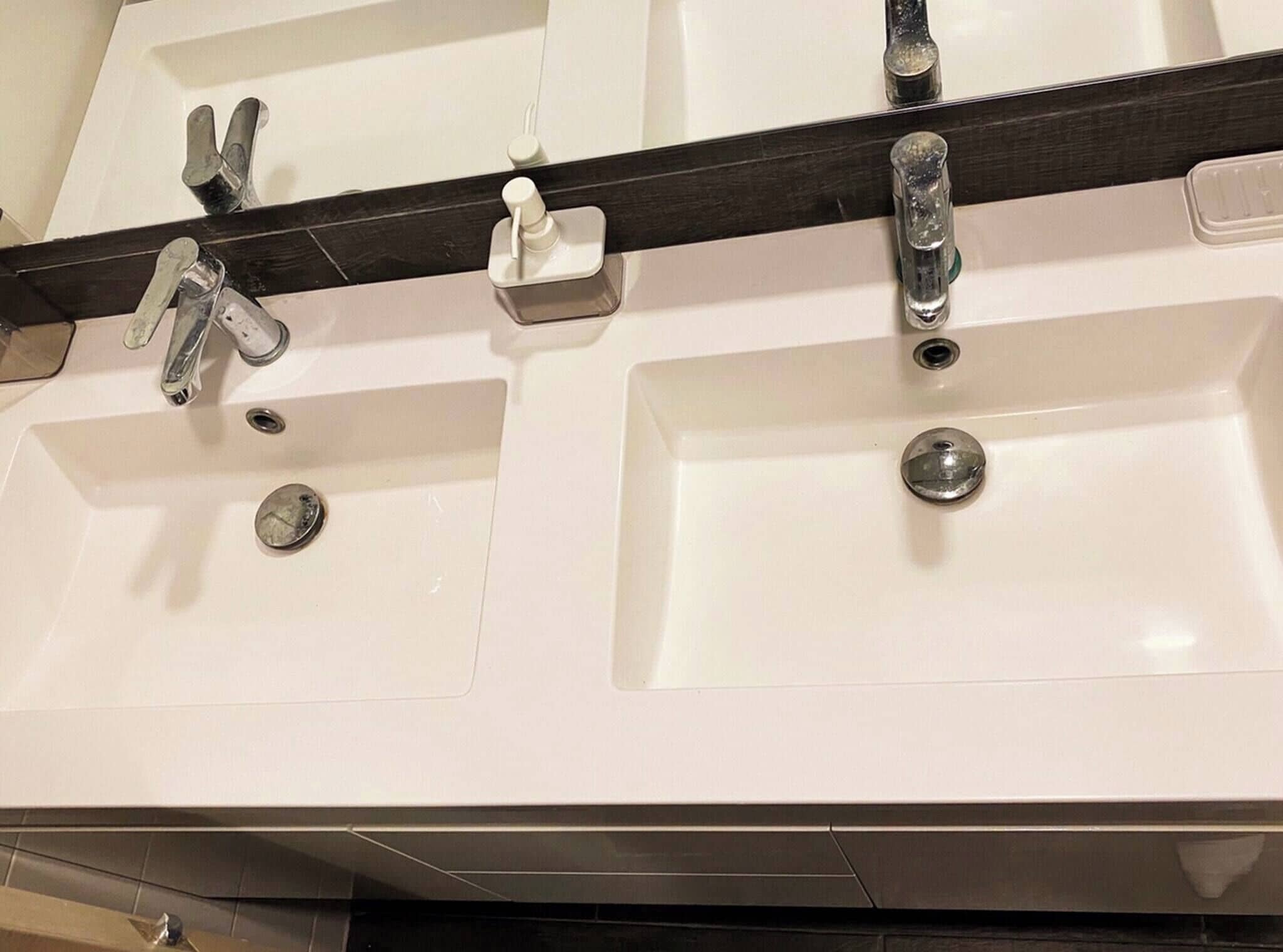 Une salle de bain avec deux lavabos, chacun équipé d’un robinet et d’un distributeur de savon.